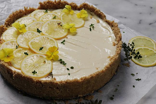 Lemon Cheese cake decorated with lemon slices and edible flowers.