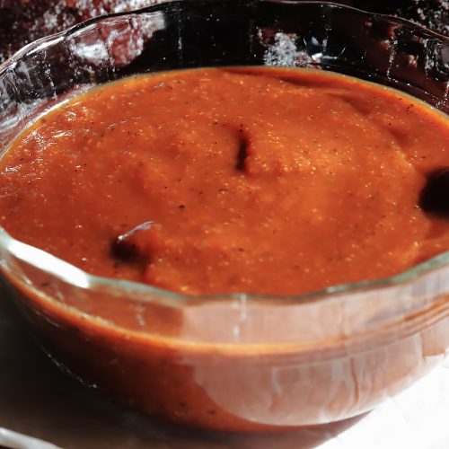 A small bowl of thick rich tomato based BBQ sauce.