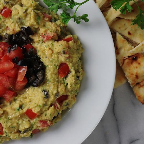 Hummus style bean dip topped with chopped tomato and olives served with pita bread.