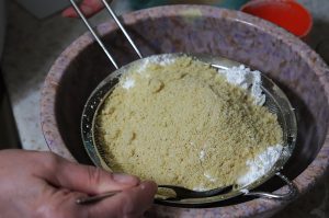 Powdered sugar and almond meal mixed together and pressed through a fine mesh sieve into a mixing bowl.
