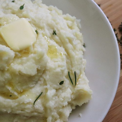 A big fluffy pile of mashed potatoes on a plate with a big pat of butter melting in the center. Delicious!