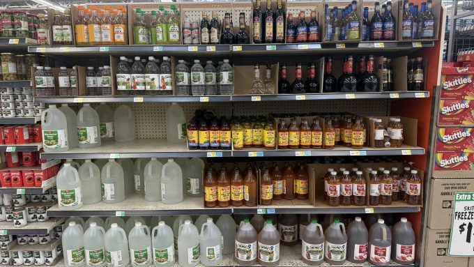 Grocery store shelves filled with many different kinds of vinegar in many sizes and shapes of bottles.