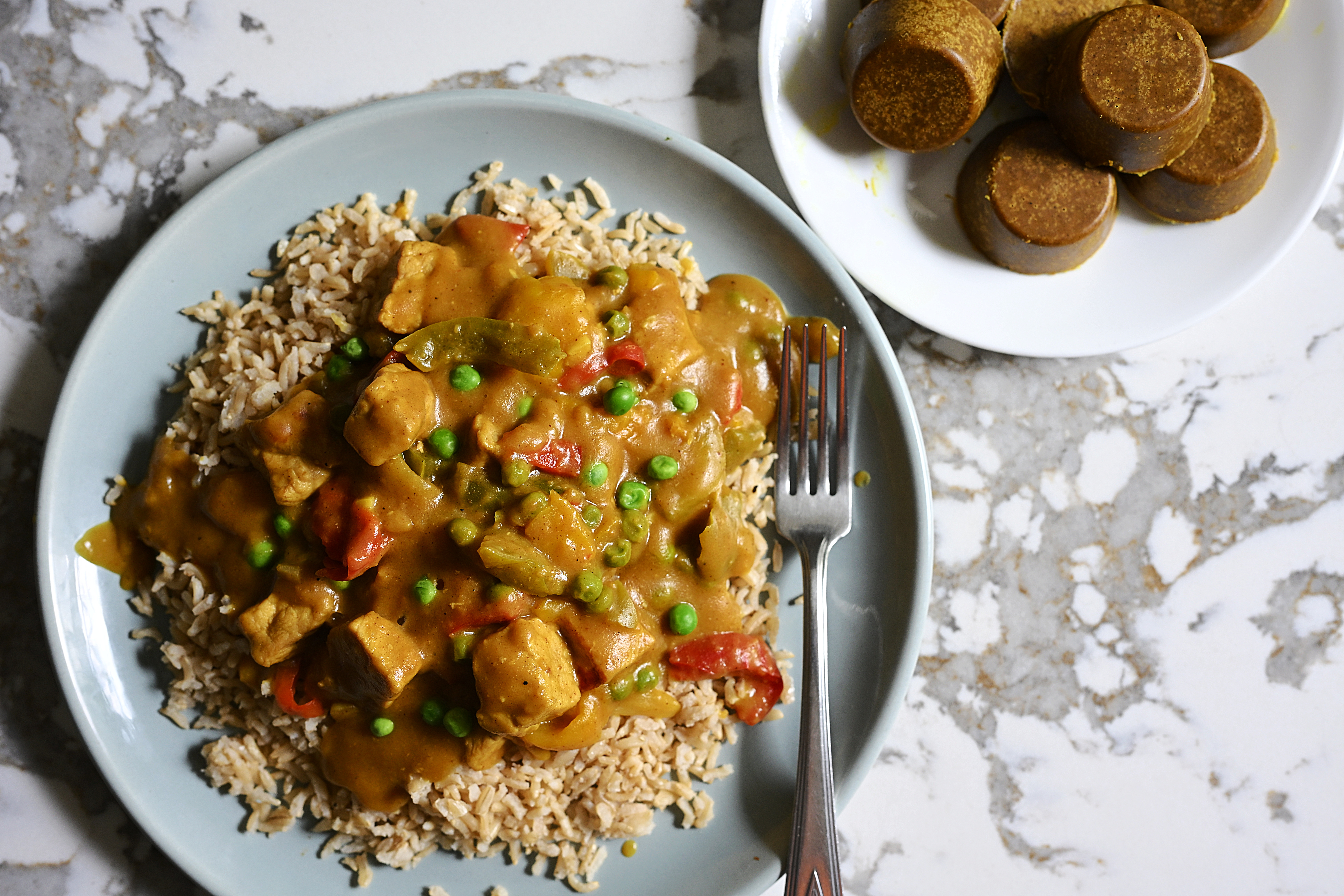 A plate of delicious, curried chicken over rice with loads of veggies. There are also disks of curry roux, used to make this curry easily and inexpensively. The recipe is in the post.