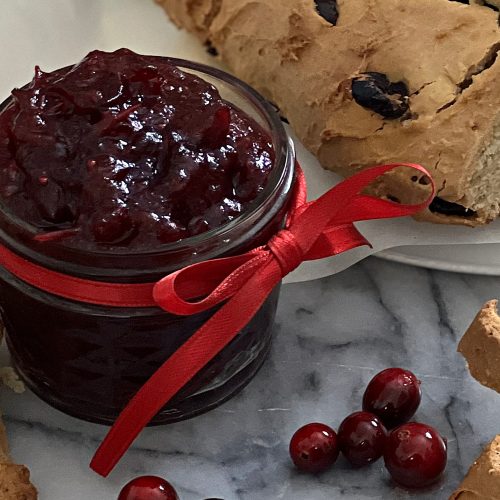 A jar of homemade cranberry orange jam, glossy, tart and sweet, delicious