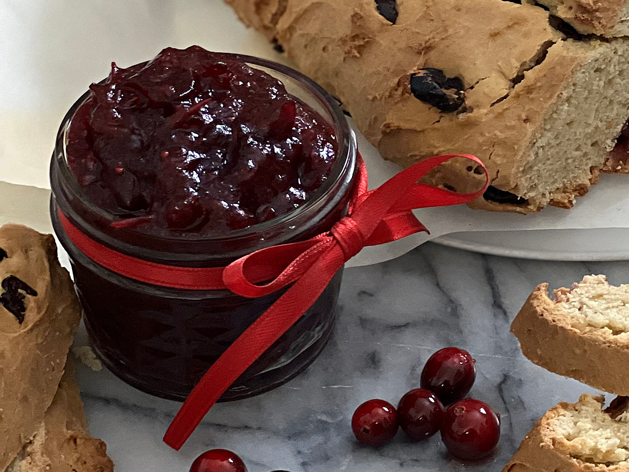 A jar of homemade cranberry orange jam, glossy, tart and sweet, delicious